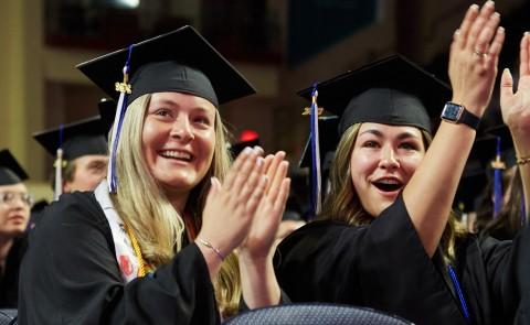 Two graduates cheer and clap during the University's Commencement ceremony 