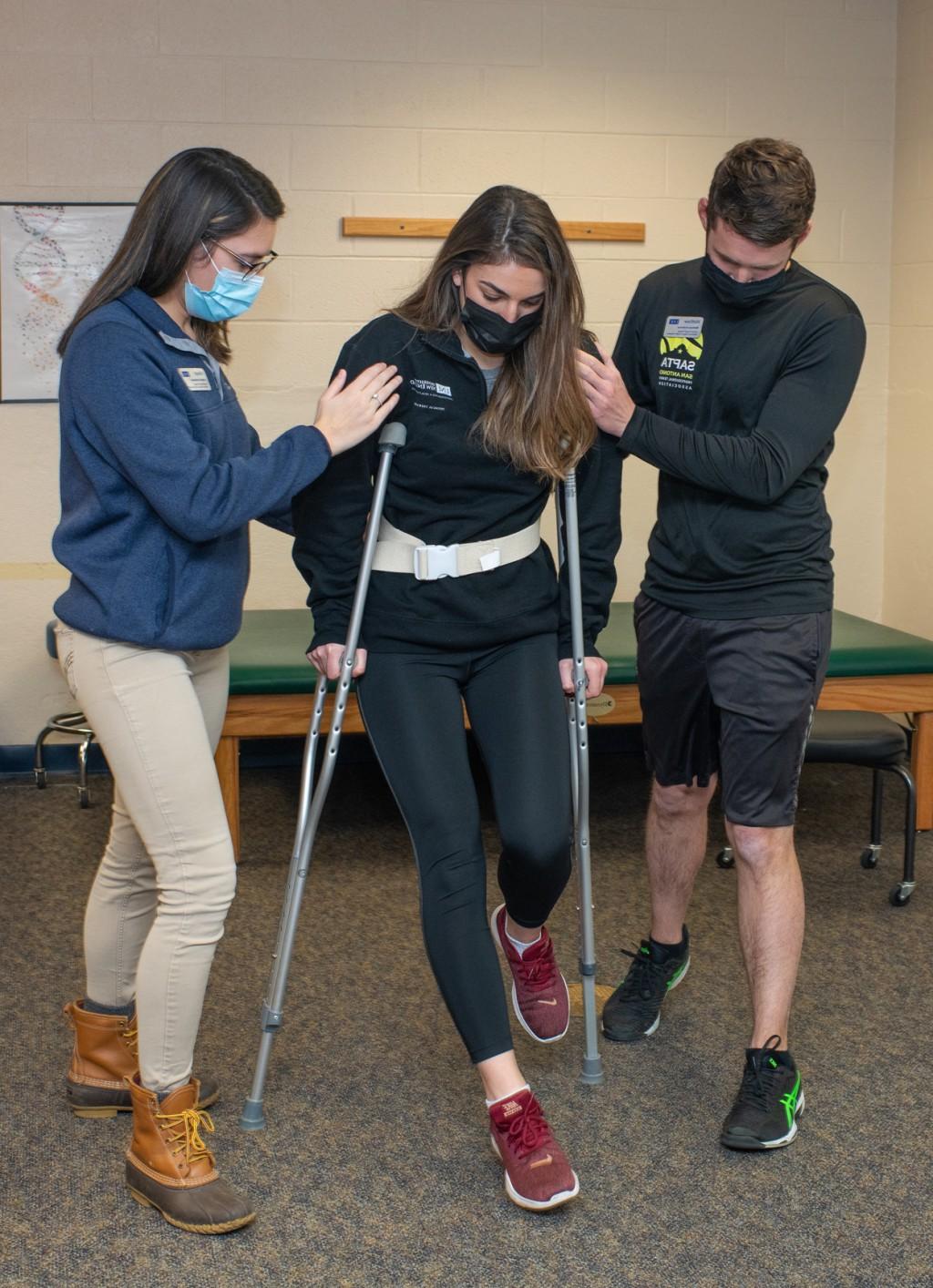 两名物理治疗专业的学生在练习帮助病人安装新拐杖